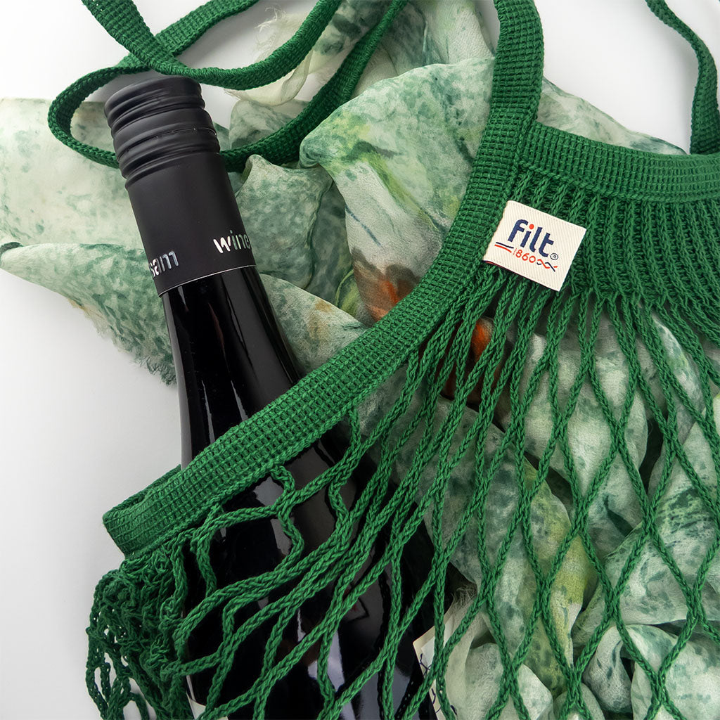 filt string bag in vert foret styled with a bottle of wine and scarf