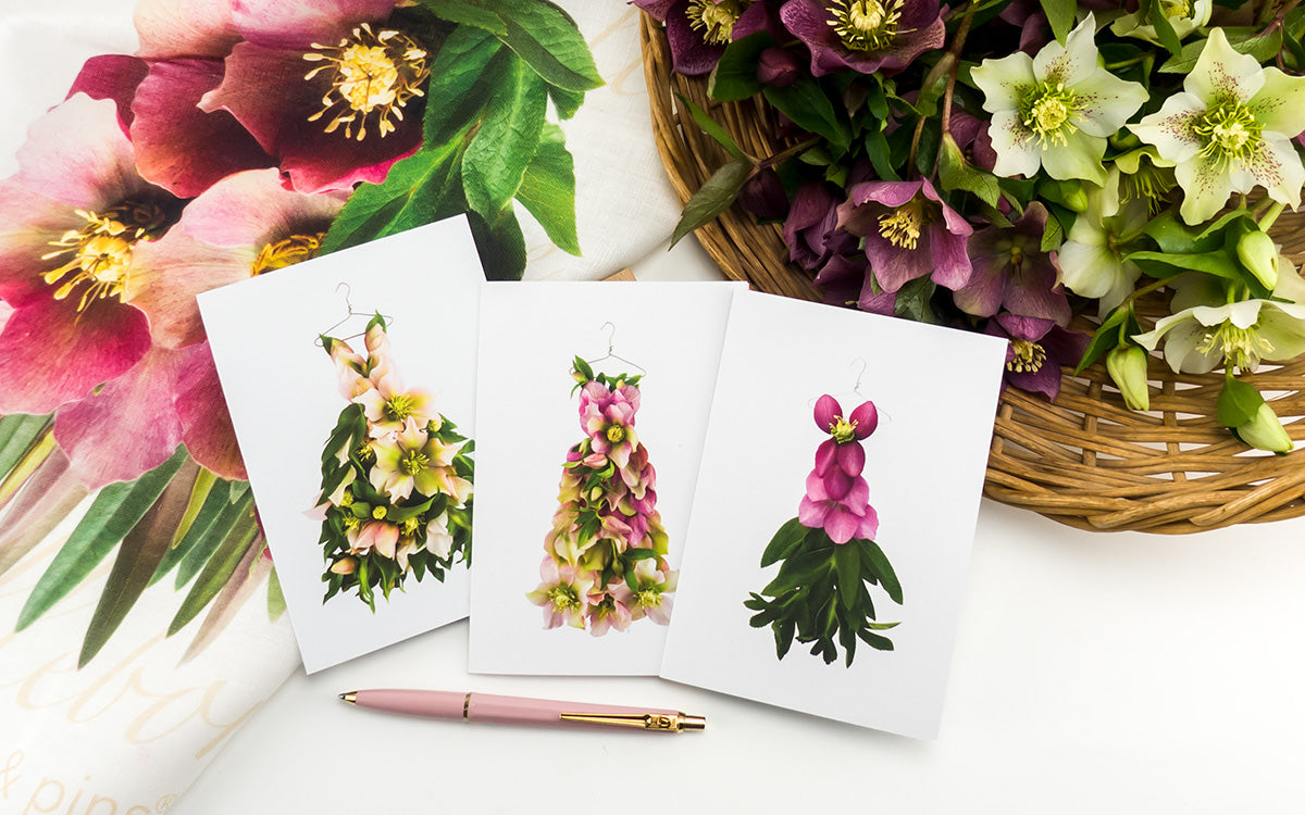 three hellebore dress greeting cards from and pure linen tea towel from the garden fairy's wardrobe by petal & pins with a basket of fresh hellebore flowers