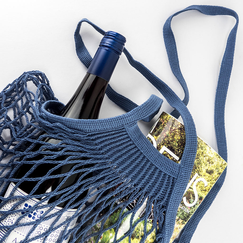 cotton string shopping bag - bleu jean - filt - styled with wine and magazine